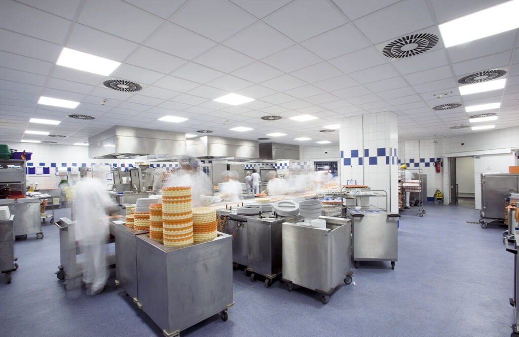 Stort kommersiellt kök upplyst av jämnt fördelade, energieffektiva LED-takarmaturer från PROLJUS AB som ger starkt bländfritt ljus för förbättrad arbetsmiljö, hygien och låg driftkostnad