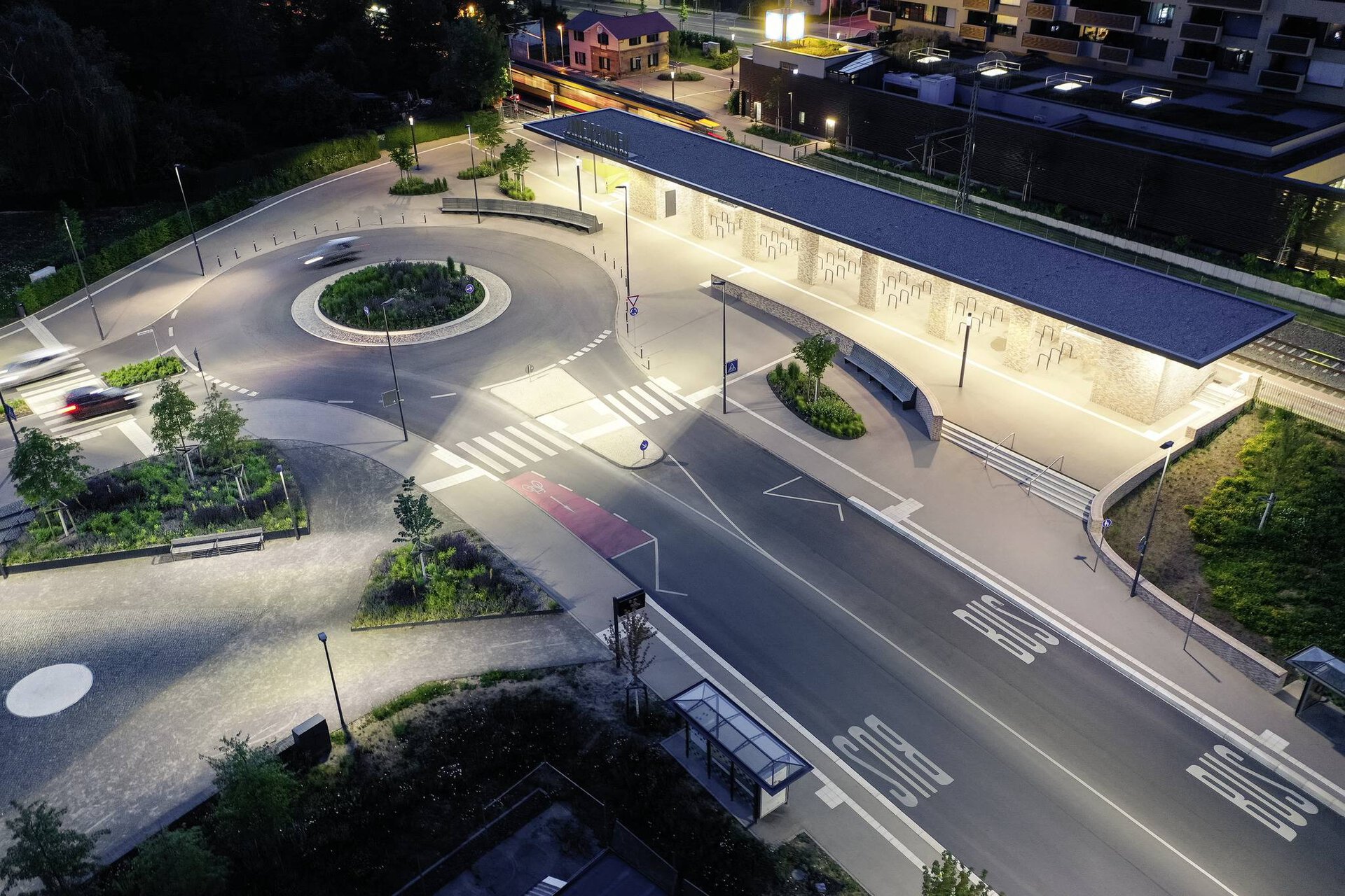 Fågelperspektiv över en modern bussterminal och rondell upplyst av energieffektiva LED-armaturer, varmvitt tak- och markljus samt slimmade stolparmaturer som visar PROLJUS ABs lösningar för säkra, energieffektiva och visuellt attraktiva offentliga miljöer