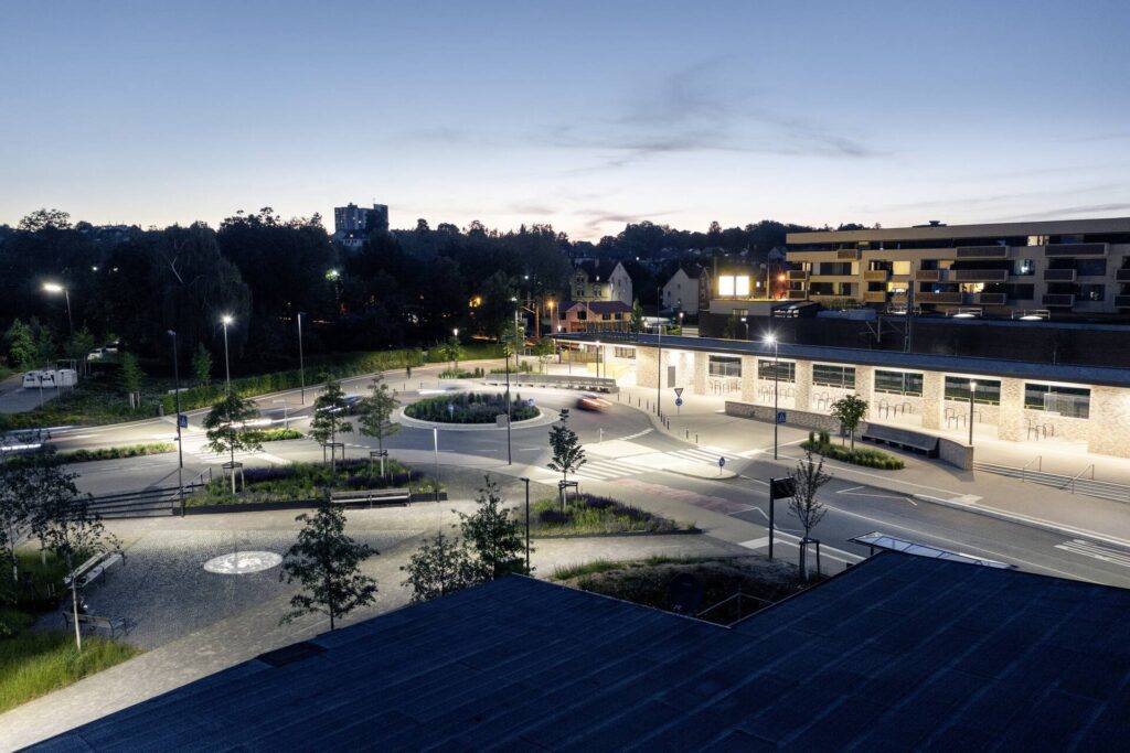 Kvällsbild över en modern rondell och gångytor upplysta av PROLJUS AB:s energieffektiva LED-armaturer som ger jämnt, varmt ljus, förbättrad sikt och ökad trygghet i stadsmiljön