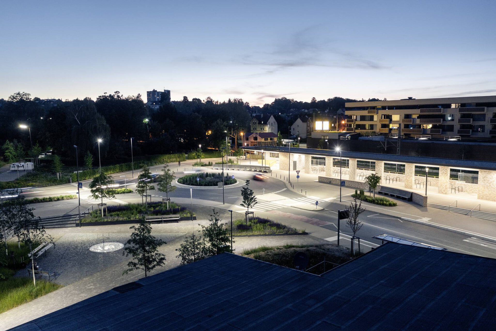 Kvällsbild över en modern rondell och gångytor upplysta av PROLJUS AB:s energieffektiva LED-armaturer som ger jämnt, varmt ljus, förbättrad sikt och ökad trygghet i stadsmiljön