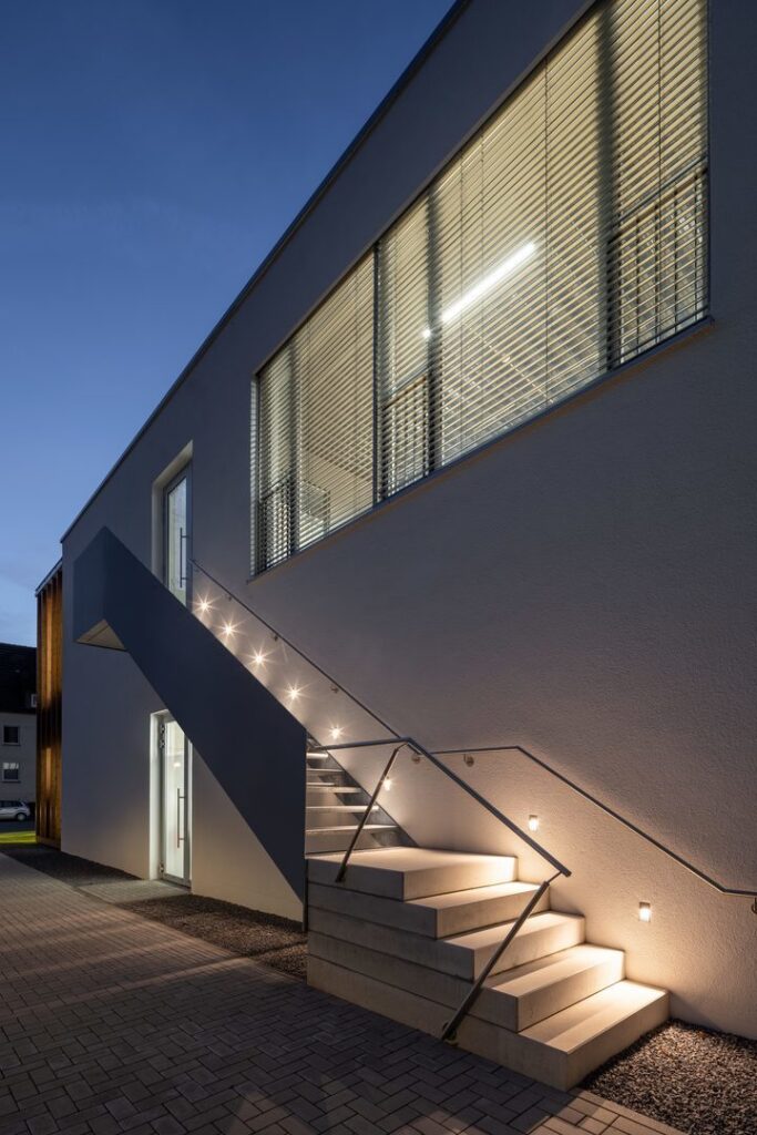 Exteriörbild av modern betongtrappa upplyst av diskreta och energieffektiva LED-armaturer från PROLJUS AB, med inbyggda steg- och vägglampor som skapar säker, jämn och säljande fasadbelysning