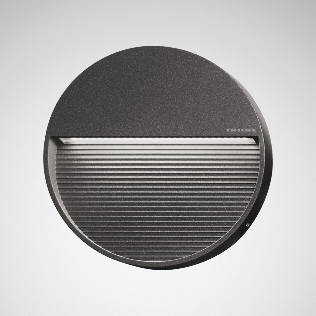 Rund mörkgrå väggarmatur i metall med horisontell LED‑öppning och ribbad nedre yta, energieffektiv modern design från PROLJUS AB som ger mjuk riktad belysning för både inomhus och utomhus