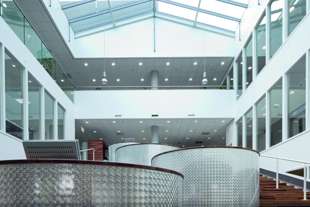 Modernt atriumkontor med jämn belysning från infällda downlights i taket och tre eleganta pendellampor över trappan, tydlig visning av PROLJUS ABs energieffektiva och designade armaturer