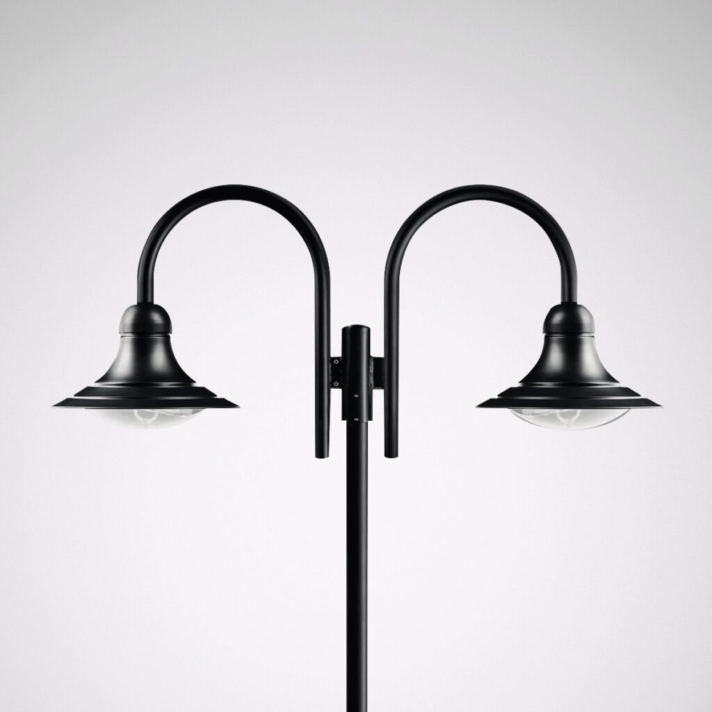 PROLJUS AB:s eleganta dubbelarmade gatlykta i matt svart med svepande bågar, kupformade skärmar och klarglas som ger varm och riktad utomhusbelysning, perfekt för parker, promenadstråk och kommersiella miljöer