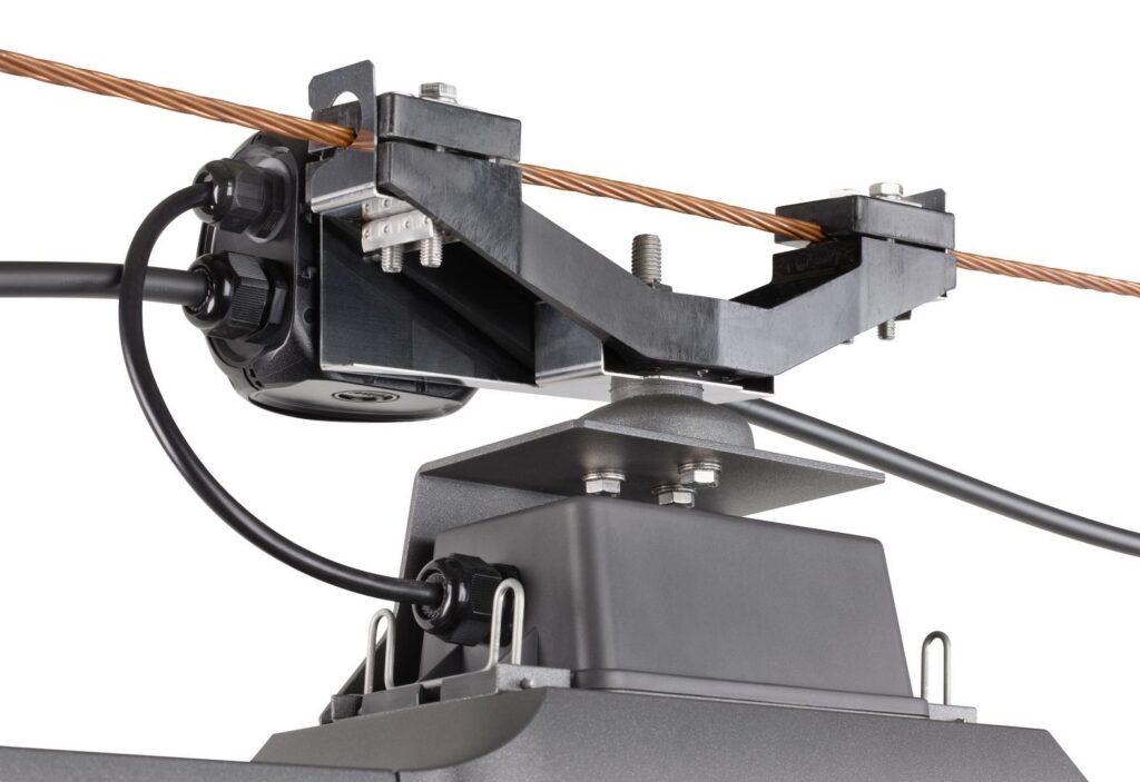 Närbild på PROLJUS AB linjärarmatur med robust metallfäste och tät kabelgenomföring monterad på kopparbärlina, professionell, väderskyddad och lättinstallerad lösning för industri- och kommersiell belysning