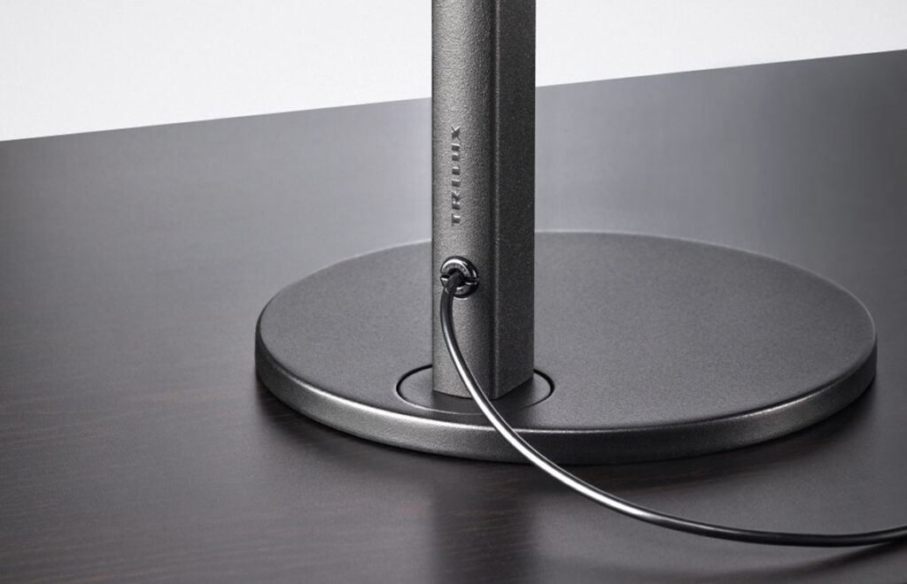 Detaljbild av PROLJUS ABs premium bordsarmatur med rund metallfot, slank stolpe och diskret kabelgenomföring i matt grafitfinish, en stabil och elegant arbetslampa för kontor och hem