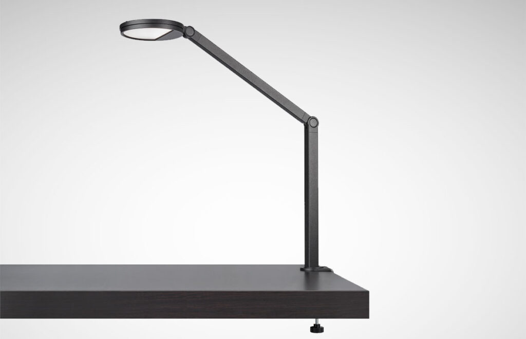 Justerbar svart LED-skrivbordslampa med rund diffusor och två ledade armar som kläms fast i bordskant, modern energieffektiv design från PROLJUS AB som förhöjer arbetsplatsbelysningen