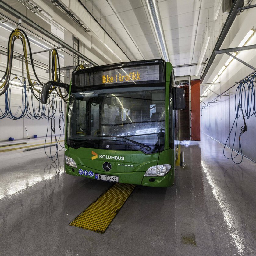 Inomhus busstvätt där långa linjära LED-armaturer från PROLJUS AB i taket ger jämn, stark och energieffektiv belysning som framhäver den blanka gröna bussen och underlättar säkert arbete och fordonsvård