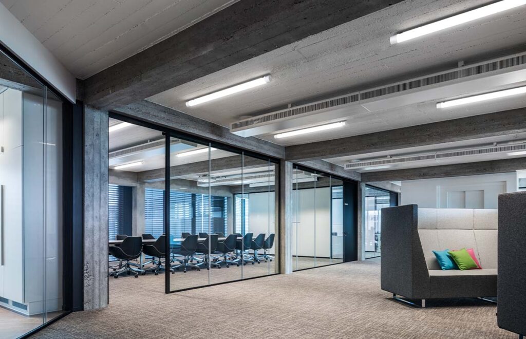 Modernt kontorslandskap med slimmade linjära takarmaturer från PROLJUS AB som ger jämnt bländfritt LED‑ljus, energieffektiv drift och stilren design perfekt för konferensrum och öppna kontorsytor