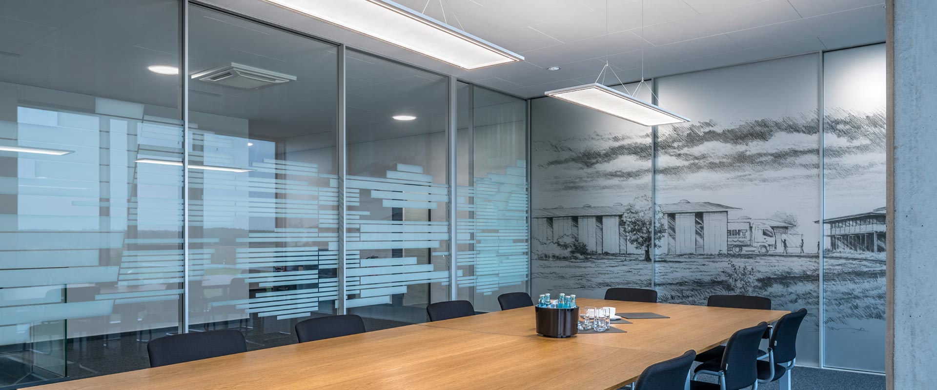 Konferensrum med två slimmade, hängande rektangulära LED-armaturer som ger jämnt, bländfritt och energieffektivt arbetsljus över bordet, modern och diskret design perfekt för kontor, levererade av PROLJUS AB