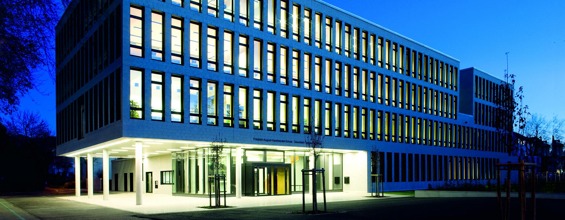 Kvällsbild av modern kontorsbyggnad belyst av PROLJUS AB med varmvita, energieffektiva LED-armaturer i fasad och entré som ger jämnt, arkitekturanpassat ljus, sparar energi och skapar ett tryggt och välkomnande intryck