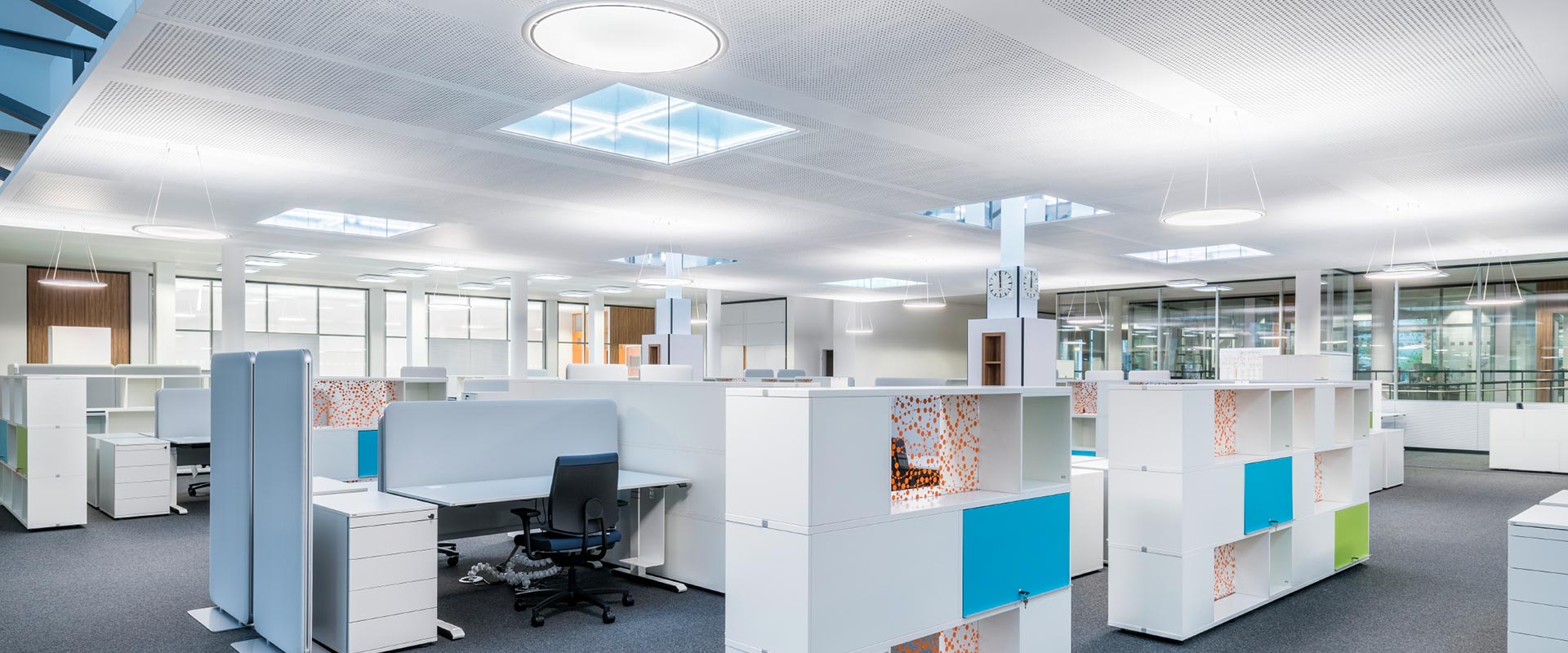 Modernt kontorslandskap upplyst av eleganta PROLJUS AB-takarmaturer med runda hängande armaturer och kvadratiska infällda paneler som ger jämn, bländfri och energieffektiv belysning för en produktiv och stilren arbetsmiljö