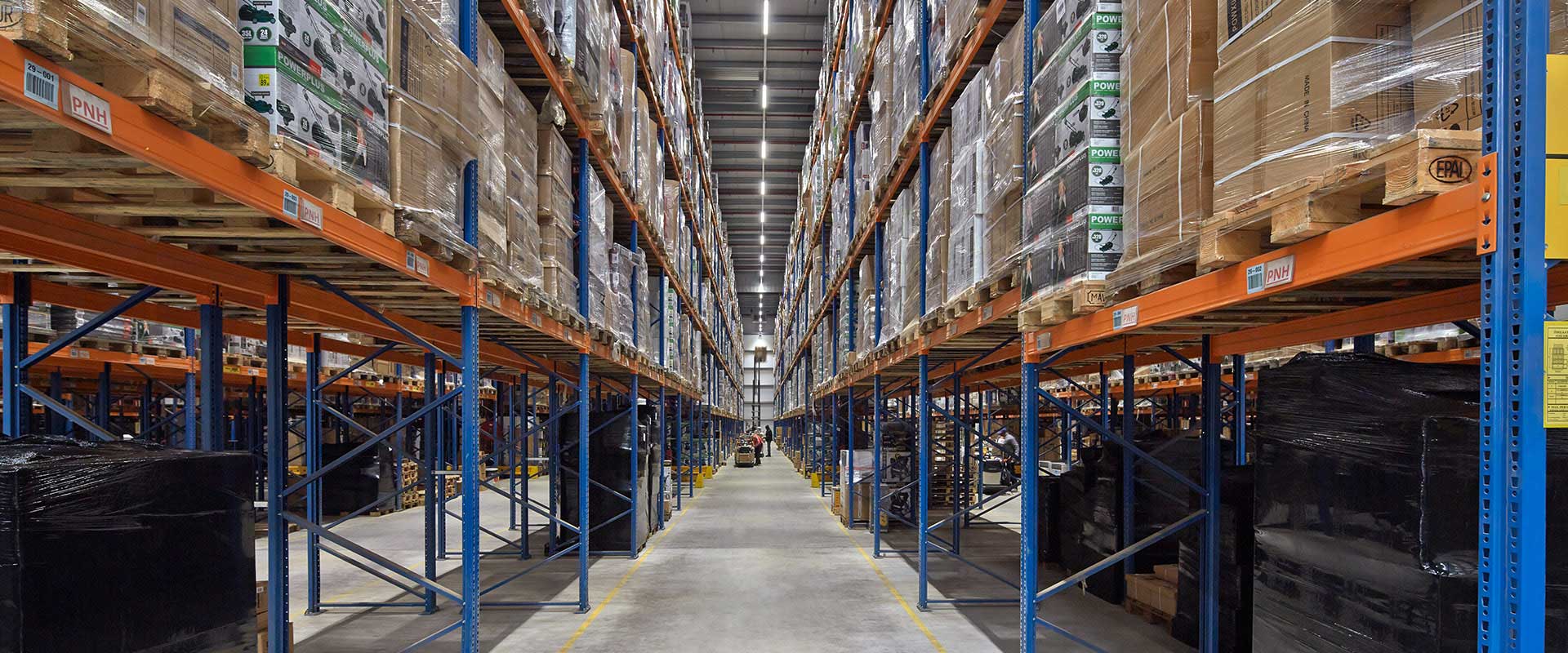 Stor lagergång upplyst av jämna, energieffektiva takarmaturer som visar PROLJUS ABs LED-lösningar för stark, bländfri arbetsbelysning, förbättrad säkerhet och lägre energikostnader