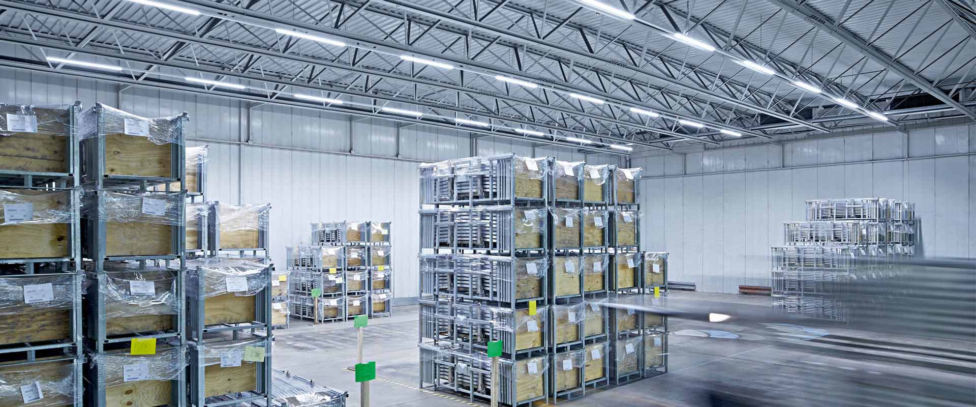 Rymligt industriellt lager upplyst av PROLJUS ABs slimmade, energieffektiva LED-armaturer monterade i takbalkarna som ger jämnt, starkt arbetsljus, minskar energikostnader och förbättrar säkerhet och produktivitet i industrimiljöer