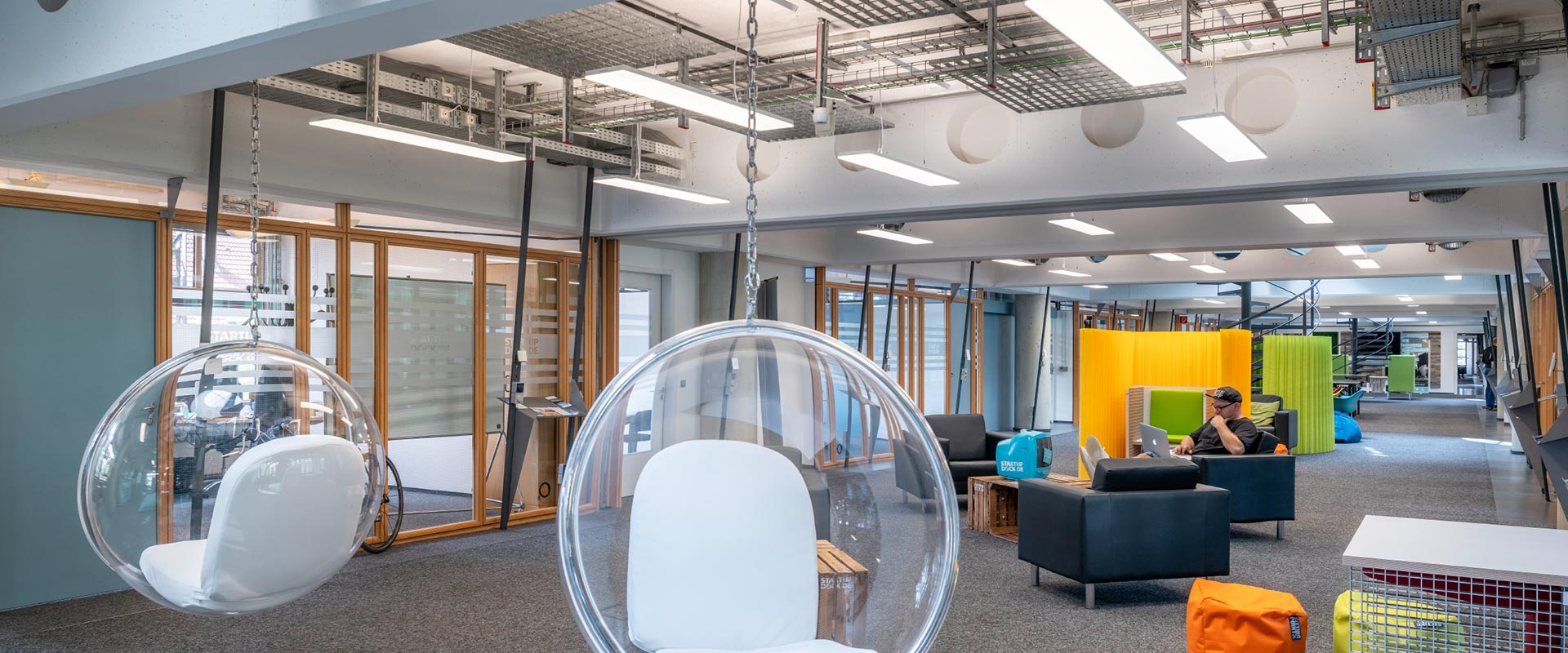 Öppet kontorslandskap med långa hängande linjära LED-armaturer som ger jämnt och bländfritt arbetsljus, synliga kabelbanor och modern industriell estetik, energieffektiva belysningslösningar från PROLJUS AB