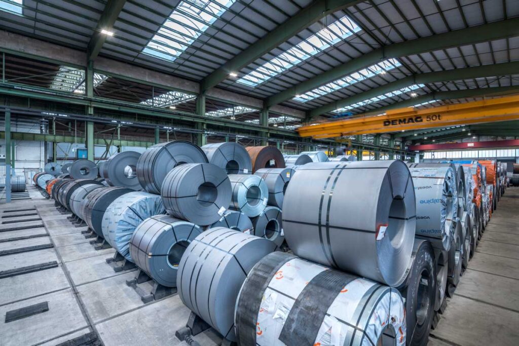 Stor industrilokal med rader av stålspolar upplyst av PROLJUS AB:s energieffektiva LED-armaturer som ger klart, jämnt arbetsljus, robust konstruktion och lägre driftkostnader perfekt för lager och fabriksmiljöer