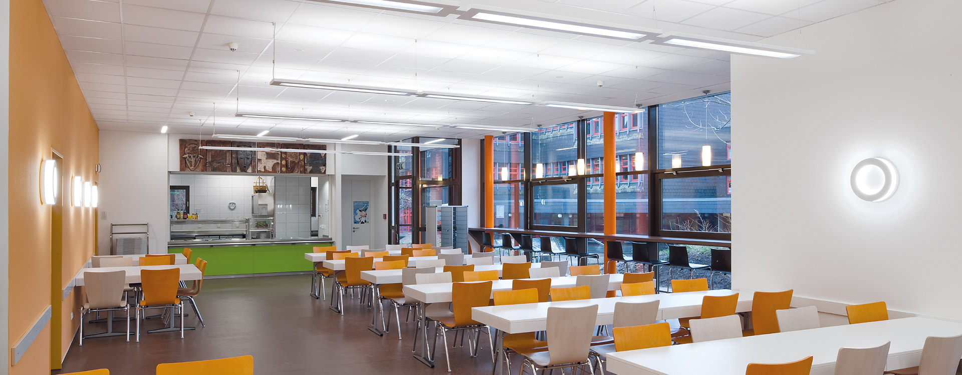 Modern skolmatsal upplyst av PROLJUS ABs energieffektiva linjära takpendlar och cirkulära väggarmaturer som ger jämn, bländfri och kostnadseffektiv belysning