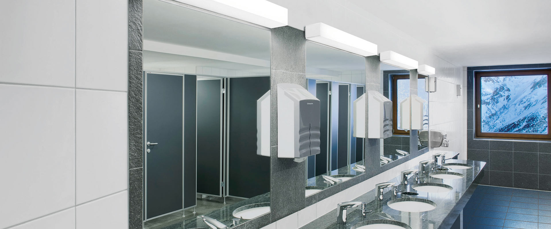 Offentlig toalett med speglar och PROLJUS ABs långa rektangulära LED-armaturer monterade ovanför som ger jämnt, bländfritt och energieffektivt ljus och förhöjer designen