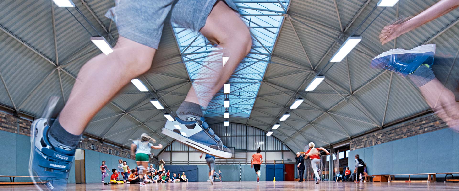 Idrottshall med en rad moderna LED-takarmaturer som ger jämnt, bländfritt och energisnålt ljus, perfekt för sportanläggningar och levereras av PROLJUS AB