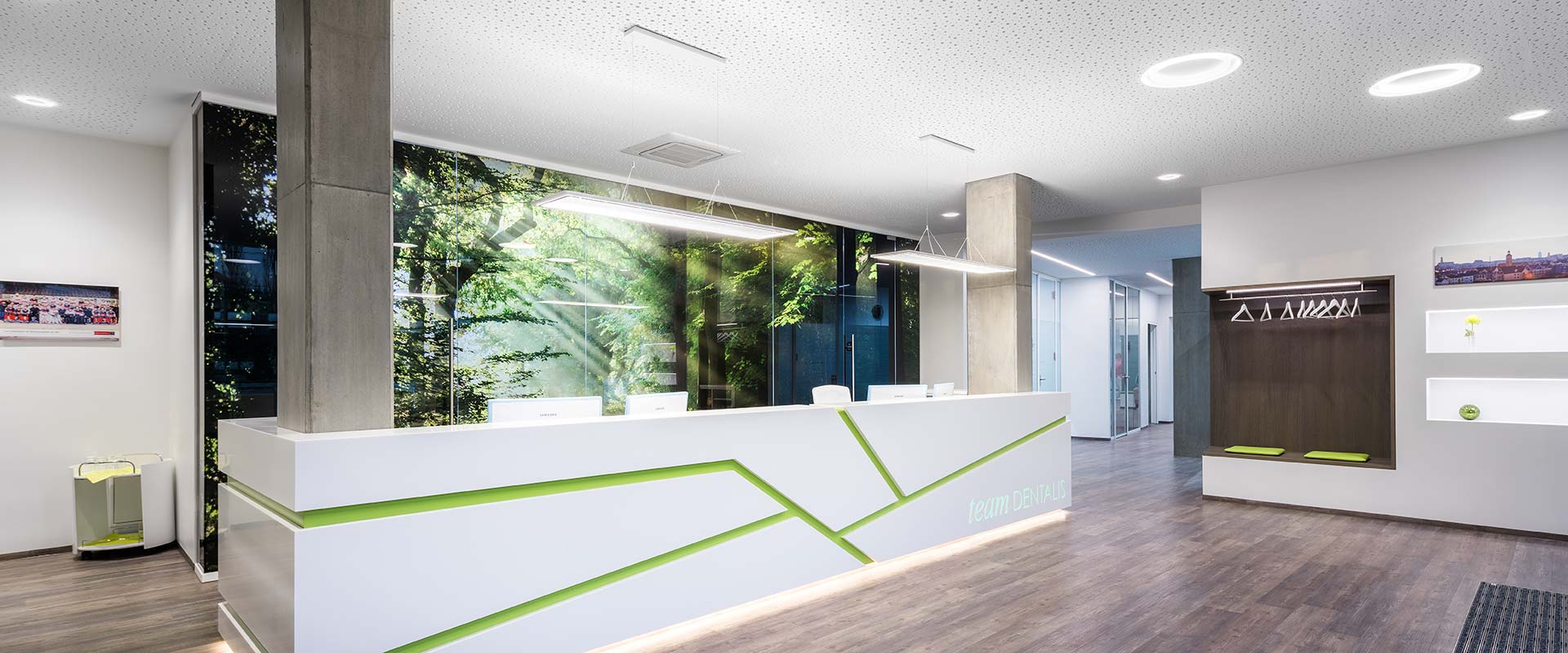 Modern reception belyst med PROLJUS AB:s armaturer med avlånga hängande LED-paneler över disken, cirkulära infällda taklampor och integrerade LED-lister i receptionsdiskens kant som skapar mjukt, energieffektivt och designad belysning från PROLJUS AB