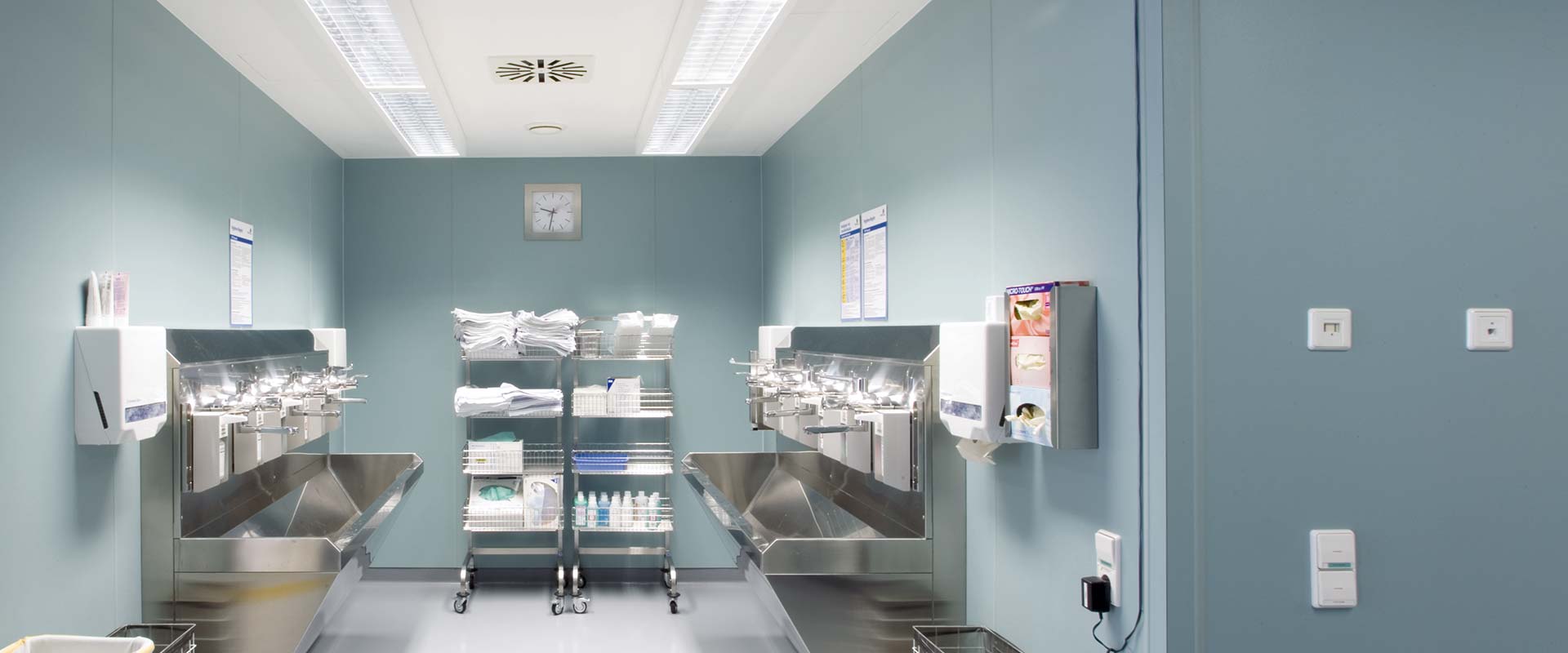 Sterilt sjukhusberedningsrum upplyst av infällda rektangulära takarmaturer från PROLJUS AB som ger bländfritt, jämnt och energieffektivt arbetsljus över rostfria tvättstationer och förbrukningshyllor