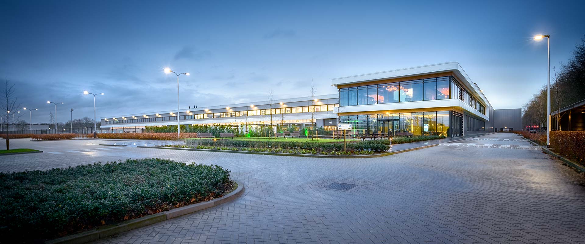 Skymningsvy av modern kontorsbyggnad upplyst av PROLJUS AB:s eleganta LED-armaturer och pollare som ger jämnt, energieffektivt och välbalanserat ljus som framhäver arkitekturen och ökar säkerhet och trivsel, kontakta PROLJUS AB för skräddarsydda belysningslösningar