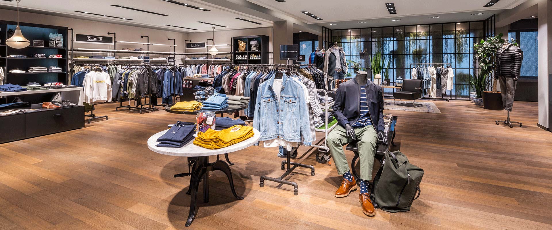 Varm butikbelysning med infällda takspotlights och eleganta pendellampor som framhäver kläder och skapar en inbjudande atmosfär, PROLJUS AB levererar energieffektiva armaturer och skräddarsydd belysning som ökar försäljningen