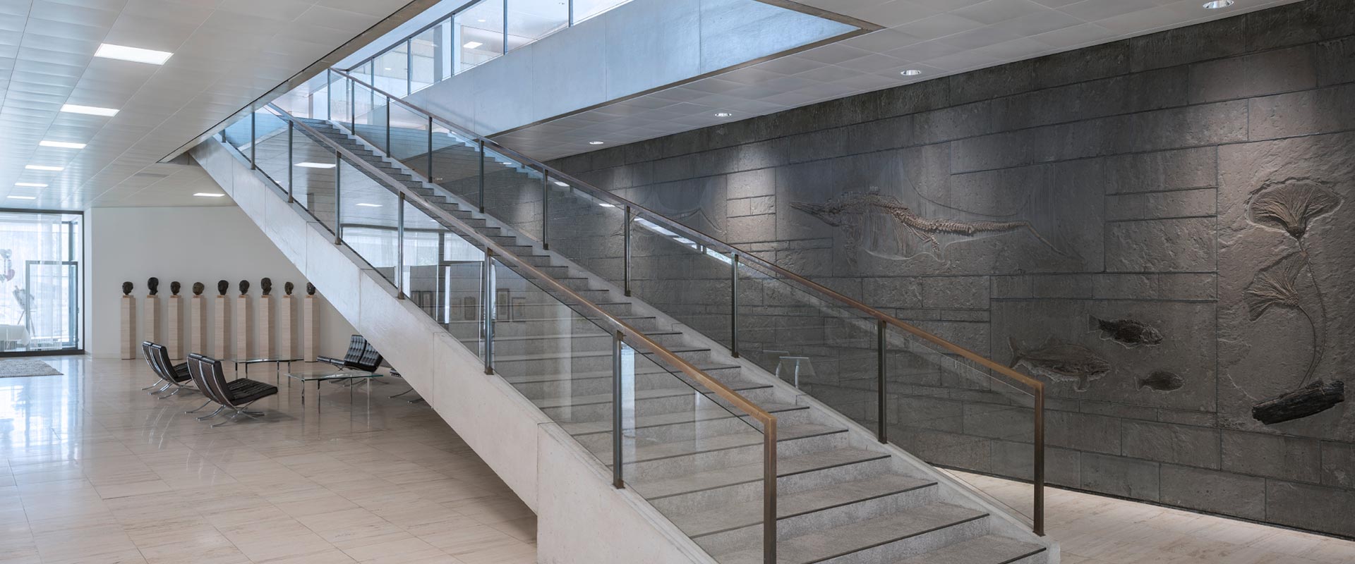 Ljusstark entréhall med jämnt fördelade infällda LED-paneler i taket och dämpade downlights som framhäver material och trappa, visar PROLJUS ABs energieffektiva lösningar för kommersiell belysning