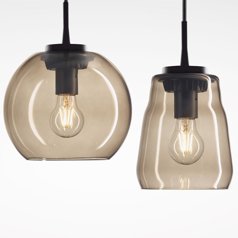 Två hängande pendellampor i rökt glas med synliga glödtrådar och svart upphängning, elegant varm belysning från PROLJUS AB