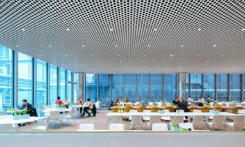 Ljus, modern matsal med ett perforerat innertak översållat med integrerade, energieffektiva PROLJUS AB LED-armaturer som ger jämn, bländfri belysning och lyfter rumsupplevelsen för kontor och offentliga miljöer