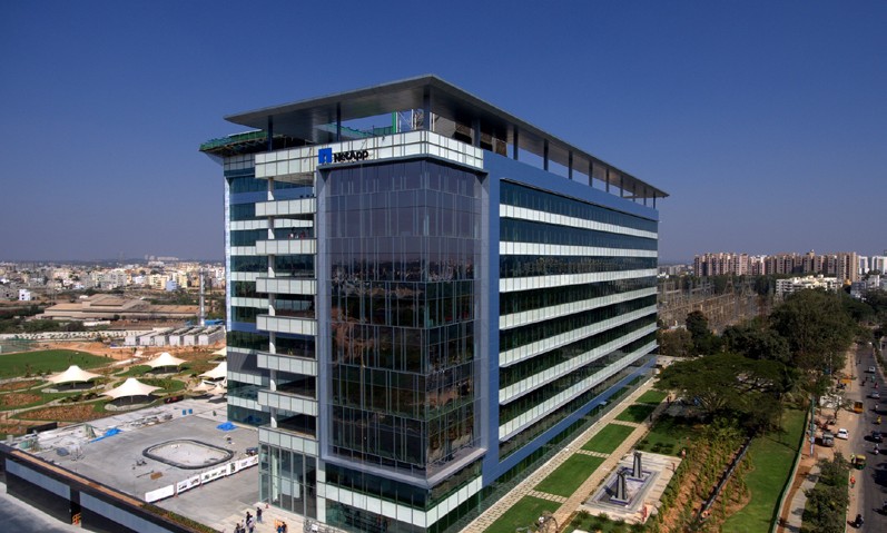 Modern kontorsbyggnad belyst av eleganta LED-armaturer som framhäver fasadens horisontella linjer, infälld markbelysning och takintegrerad belysning som skapar säkerhet och premiumkänsla, ett tydligt exempel på PROLJUS ABs energieffektiva belysningslösningar