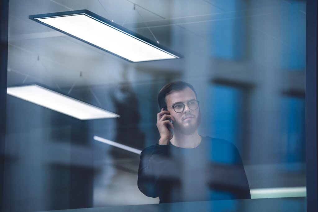 Hängande rektangulära LED-armaturer som ger mjukt, jämnt kontorsljus och reflekteras i glas — energieffektiva, designade belysningslösningar från PROLJUS AB för förbättrad arbetsmiljö och ökad försäljning