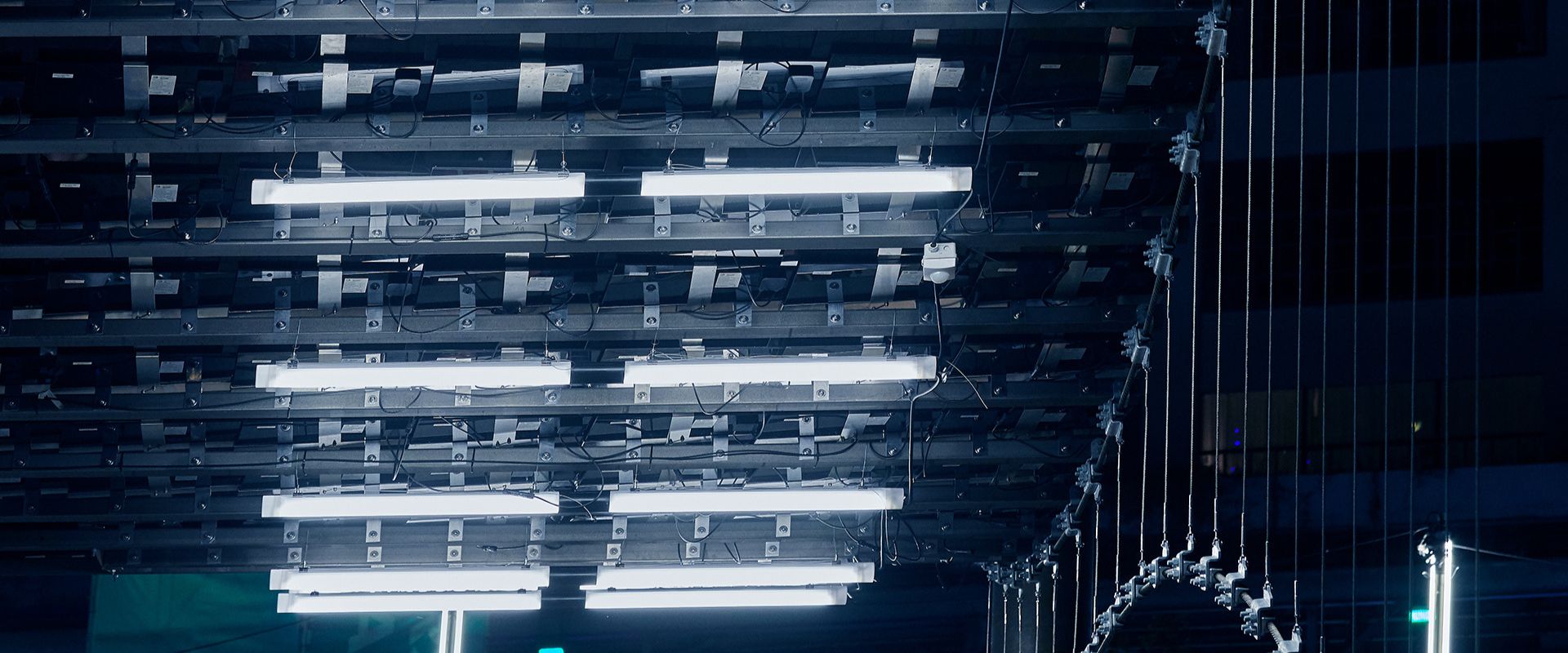 Närbild av en professionell takkonstruktion med flera rader energieffektiva lysrörsarmaturer, ordnad kabeldragning och kraftiga infästningar som visar PROLJUS AB:s högkvalitativa lösningar för jämn kommersiell belysning