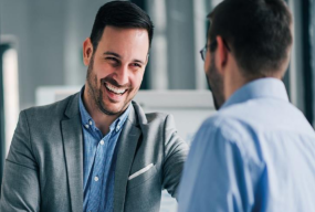 Två män i ett modernt kontor upplysta av PROLJUS AB:s varma och jämna armaturer som framhäver arbetsmiljön och underlättar professionella affärsmöten