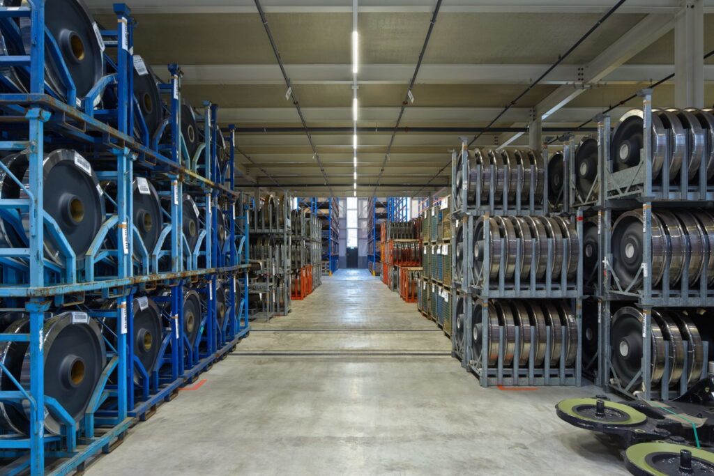 Stort lagerutrymme där en lång rad energieffektiva linjära LED-armaturer från PROLJUS AB lyser upp mittgången med starkt, jämnt arbetsljus som förbättrar säkerhet, sänker energikostnader och ökar produktiviteten, idealiskt för industriella och logistiska miljöer