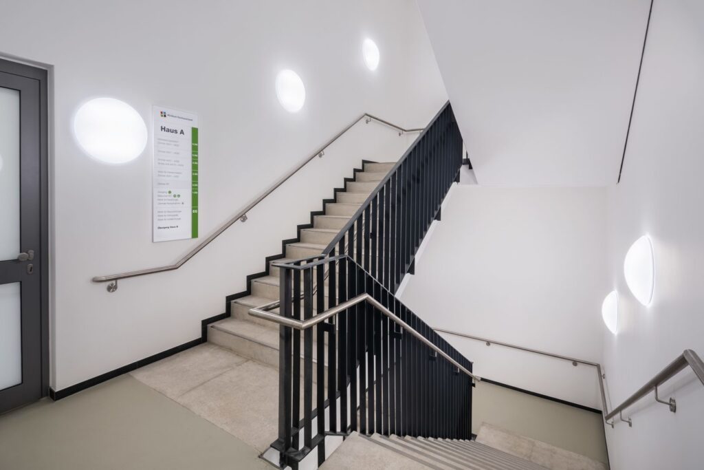 Trapphus med runda väggarmaturer från PROLJUS AB som sprider jämnt bländfritt LED-ljus och höjer säkerhet, energieffektivitet och modern design i offentliga miljöer