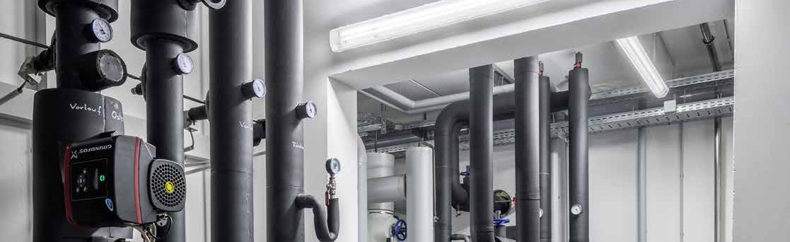 Takmonterade linjära LED-armaturer från PROLJUS AB i ett tekniskt maskinrum som ger jämnt, kraftfullt och energieffektivt arbetsljus över rörinstallationer och förbättrar både säkerhet och driftsekonomi