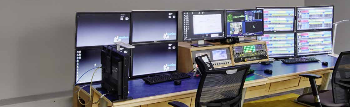 Kontrollrum med flera bildskärmar och arbetsbord upplysta av diskreta takarmaturer, riktbar skrivbordslampa och skärmljus — professionell belysning från PROLJUS AB som förbättrar sikt, ergonomi och produktivitet