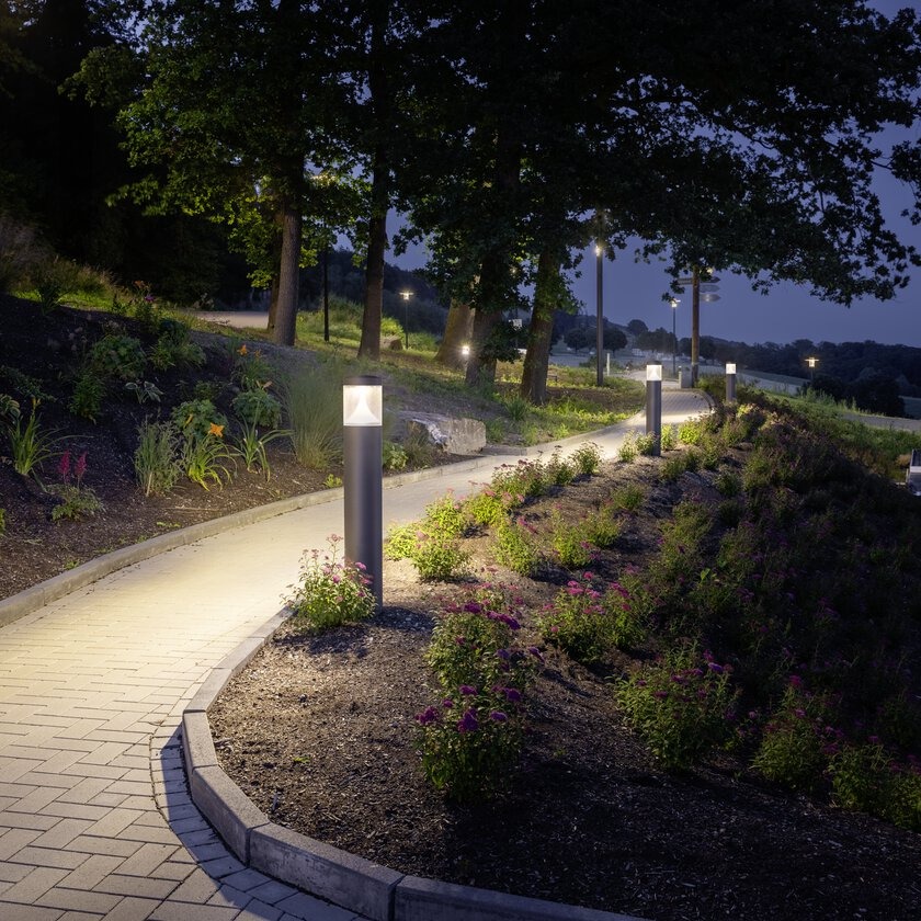 Gångväg i park upplyst av pollarljus från PROLJUS AB med varmvitt LED som ger jämn, energieffektiv vägledning och trygg, estetisk atmosfär, elegant och hållbar design för parker och offentliga miljöer
