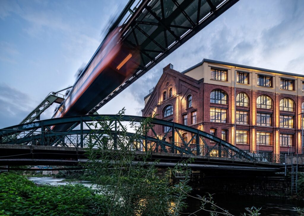 Kvällsbild där PROLJUS AB:s LED-armaturer varmt lyser upp en renoverad tegelbyggnad och bron, framhäver fasaddetaljer och fönster samt skapar en inbjudande atmosfär och ökad trygghet för kontor och kommersiella fastigheter