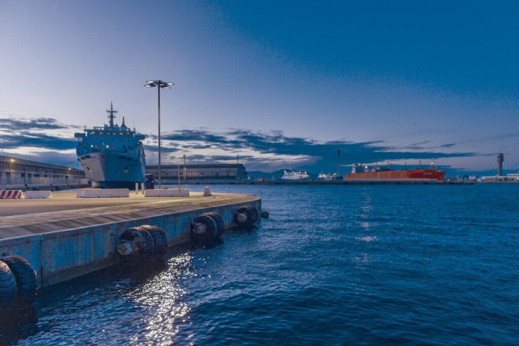 Havskaj i skymning med en hög PROLJUS AB-armatur med fyra energieffektiva LED-huvuden som kastar klart och bländfritt ljus över kajen som reflekteras i vattnet och visar en robust, korrosionsbeständig lösning som ökar säkerhet och synlighet i industriella hamnmiljöer