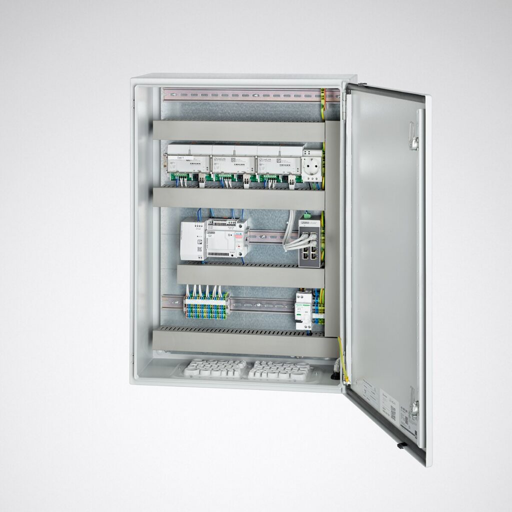 Väggmonterat öppet styrskåp med organiserade DIN-skenor, strömförsörjning och anslutningsplintar för styrning av belysningsarmaturer, professionell lösning från PROLJUS AB för pålitlig och energieffektiv belysning