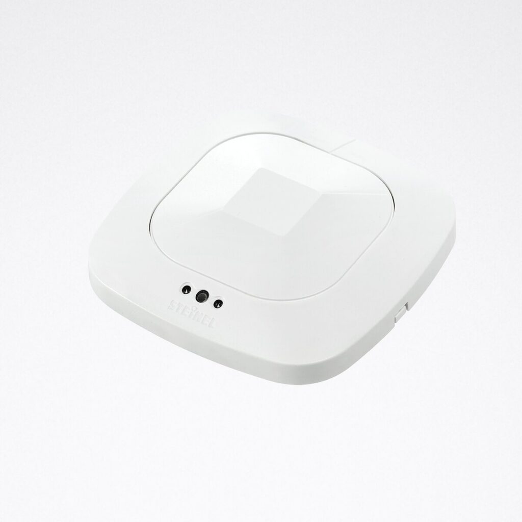 Modern vit lågprofilsarmatur med rundade kanter, central inbyggd reflektor och tre små sensorer för rörelsedetektion, energieffektiv LED-lösning för kontor, korridorer och trapphus från PROLJUS AB