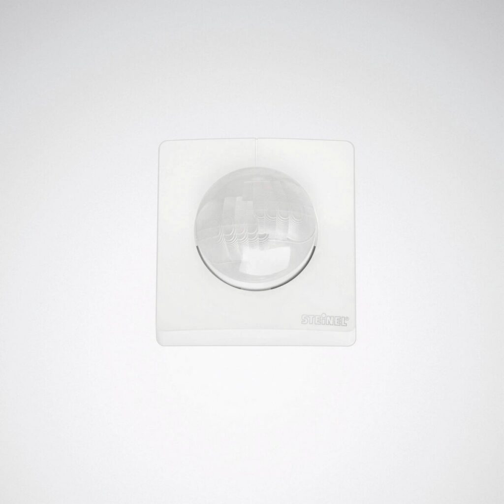 Vit väggmonterad rörelsesensor med klarglasad kupol och diskret modern design, idealisk för energieffektiva belysningslösningar från PROLJUS AB