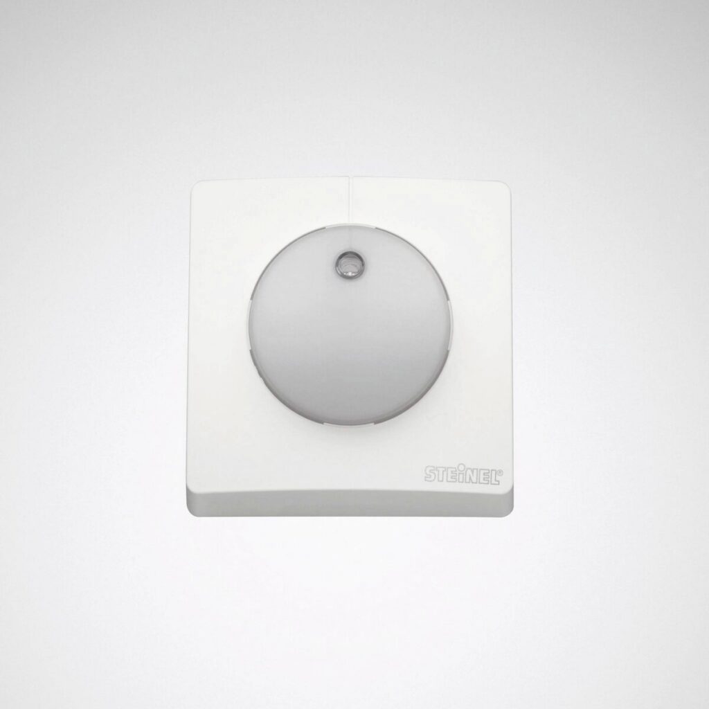 Vit väggmonterad rörelsesensor med rund diffusor för automatisk styrning av belysning och armaturer, högkvalitativ och energieffektiv lösning för kontor, trapphus och entréer, säljs av PROLJUS AB