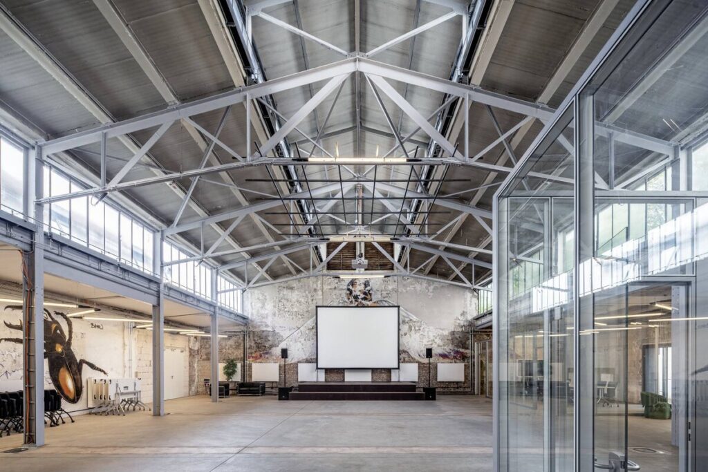 Storslagen industrilokal med synliga takstolar och eleganta linjära LEDarmaturer från PROLJUS AB som levererar jämnt kraftfullt och energieffektivt ljus idealiskt för evenemang och industrimiljöer