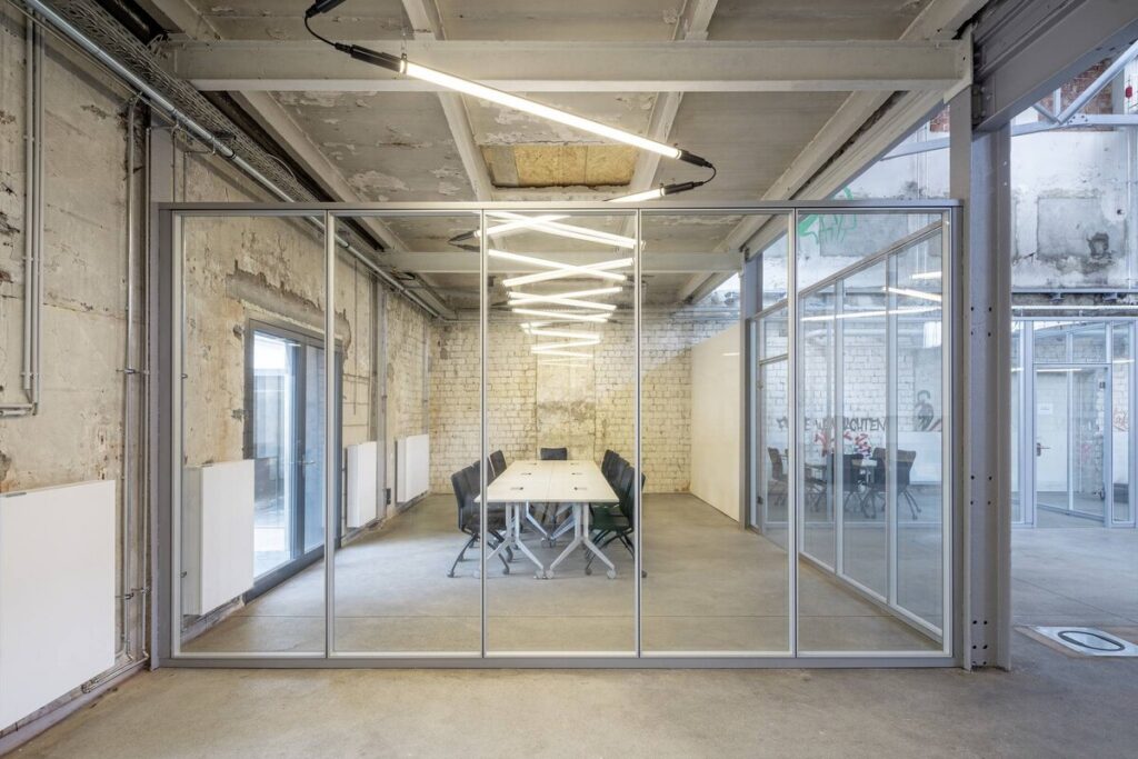 PROLJUS AB:s hängande LED-armaturer i zickzack över ett glasat konferensrum, slimmad industriell design som ger jämnt energieffektivt ljus och förhöjer moderna kontor och showrooms