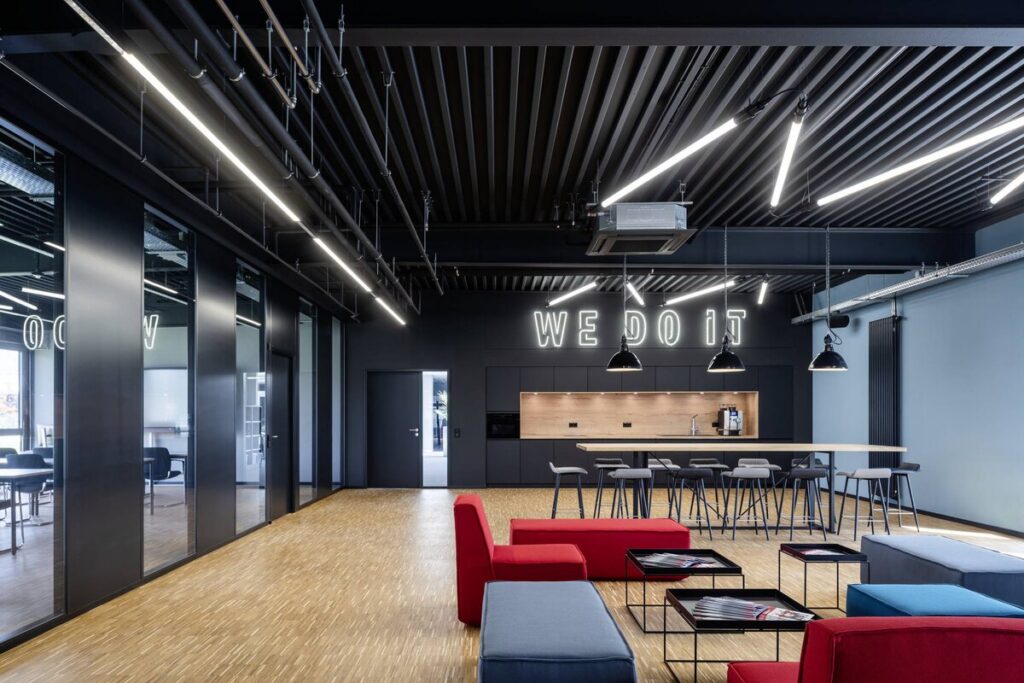 Modern kontorsyta med svart industriellt innertak, framträdande långa linjära LED-armaturer monterade i taket och svarta pendellampor över köksön som ger jämn, energieffektiv arbets- och allmänbelysning, en lösning att beställa från PROLJUS AB