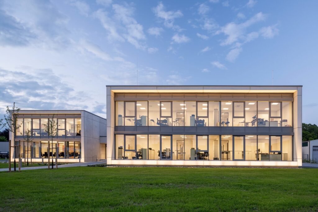 Modern kontorsbyggnad i skymning upplyst av PROLJUS ABs infällda takarmaturer, linjära LED-skenor och diskreta uplights som ger varmt, jämnt arbetsljus och framhäver fasadens arkitektur