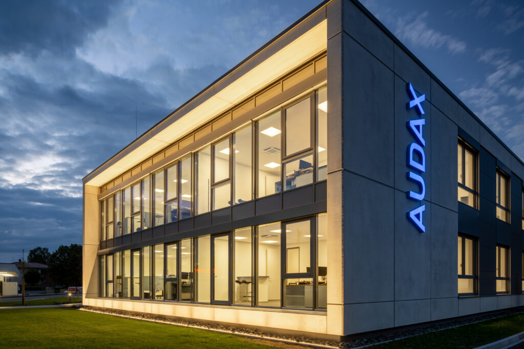 Kvällsbild av modern kontorsbyggnad där varma inomhusarmaturer och eleganta LED-lister från PROLJUS AB jämnt lyser upp glasfasaden och framhäver arkitekturen, en energieffektiv ljuslösning som ökar synlighet och trivsel